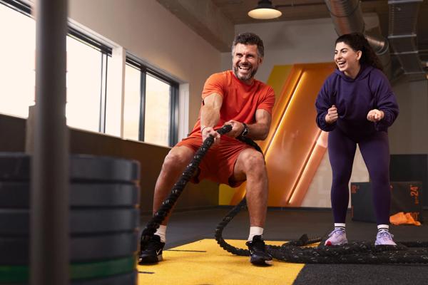 Un homme et une femme r&eacute;alisent un sled pull dans la zone HIIT & Move de Basic-Fit.
