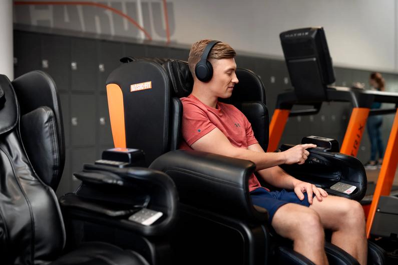 Man sitting in a massage chair at Basic-Fit.