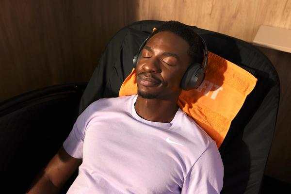 Man wearing headphones while relaxing in a massage chair at Basic-Fit.