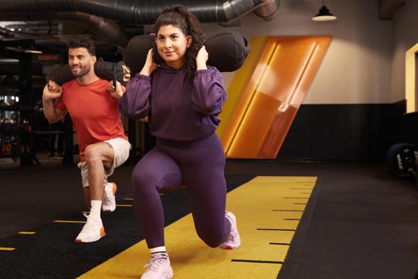 Une femme et un homme r&eacute;alisent des fentes dans la zone HIIT & Move de Basic-Fit.