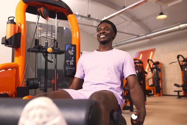 Homme r&eacute;alisant une extension des jambes dans la zone Strength Basics de Basic-Fit.